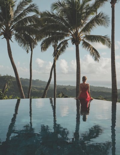 A woman wearing a flowing red dress walks towards an infinity po